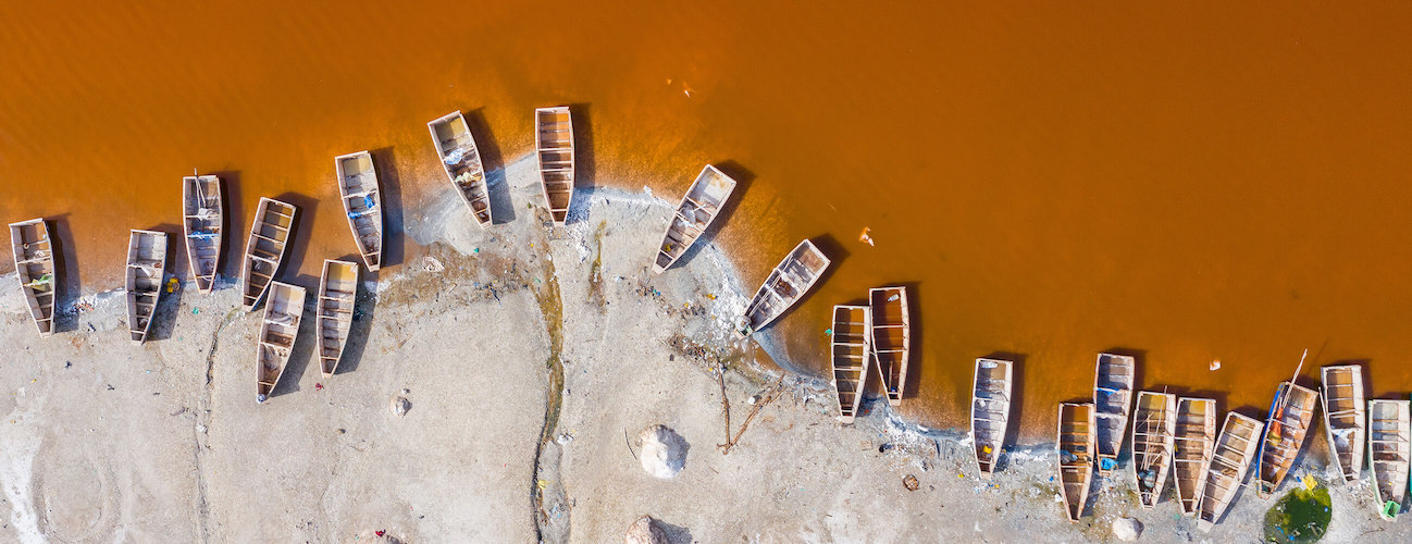 Aerial view of the small boats for salt collecting at pink Lake Retba or Lac Rose in Senegal.